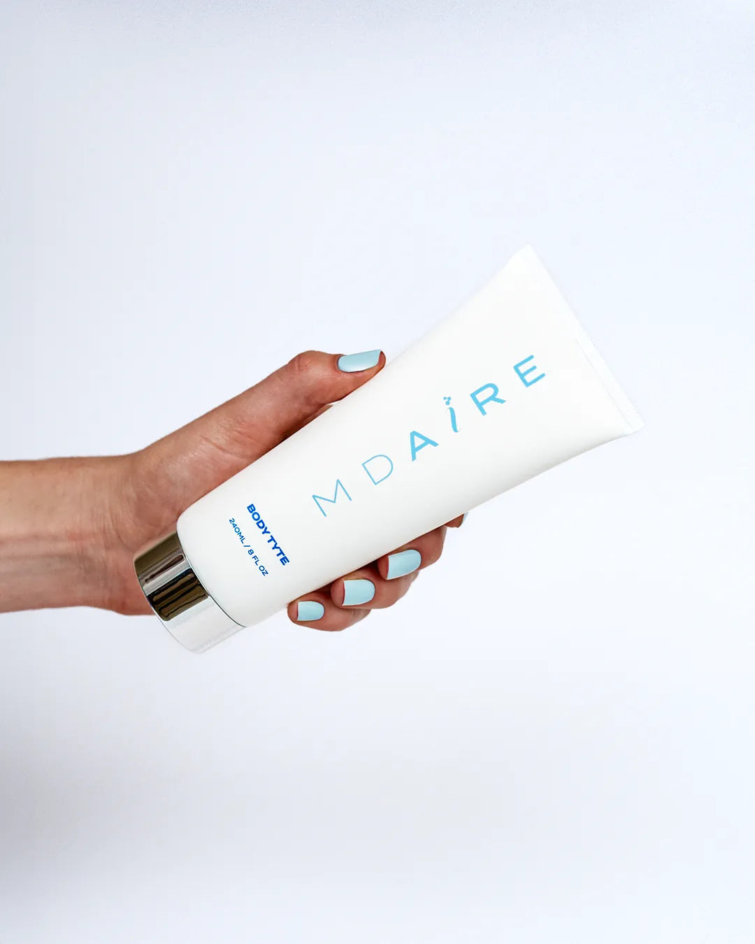 Hand holding Body Tyte tube with light blue logo and silver cap in gal