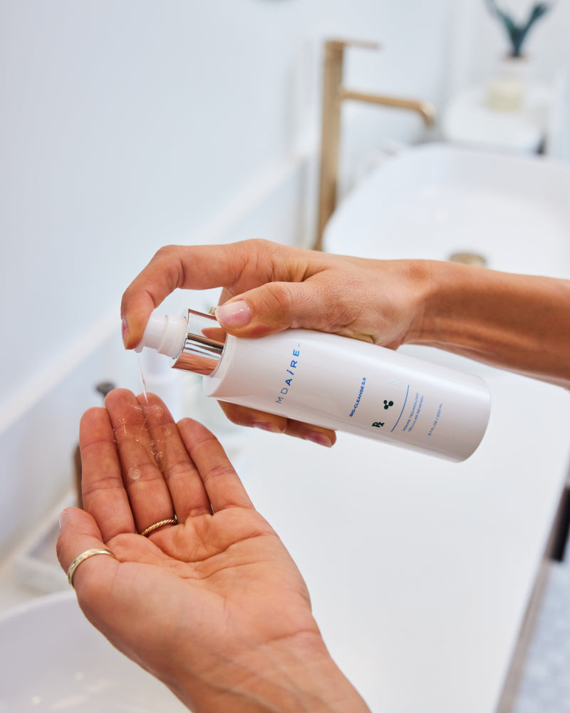 Person dispensing MDAiRE Bio-Cleanse 5.5 Face wash gel into palm over bathroom sink gallery position 1