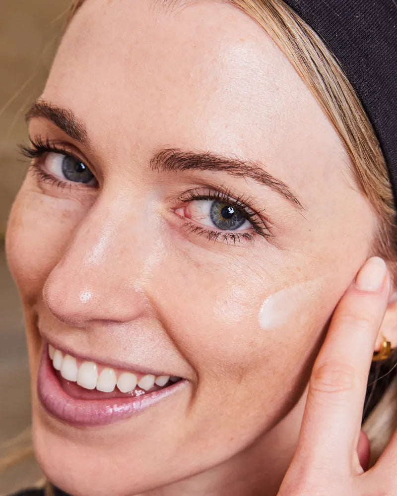 Close-up of woman applying 3-Step Glow Trio moisturizer in gallery pos
